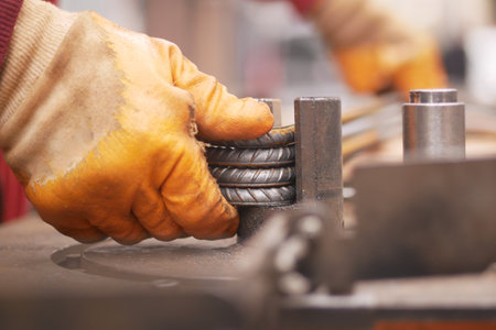 Worker shaping metal rods in a manufacturing workshopの写真素材