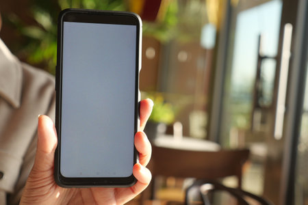 Checking a smartphone at a cafe in daylight hoursの写真素材