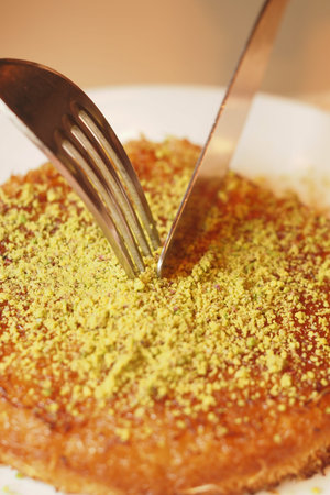 Delicious Kunefe being sliced with fork and knife for sharing