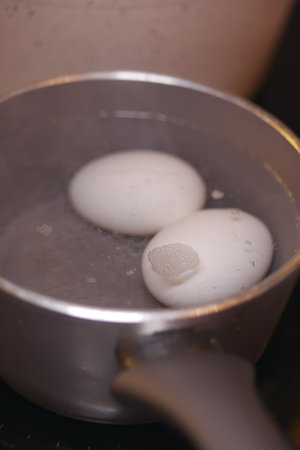 Cooking eggs in boiling water for breakfast preparationの写真素材