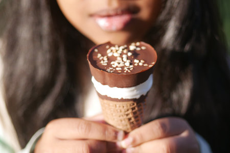 Child Enjoying a chocolate-covered ice cream cone in the sunlightの写真素材