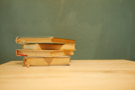 Stacked books on a wooden table against a textured wallの写真素材