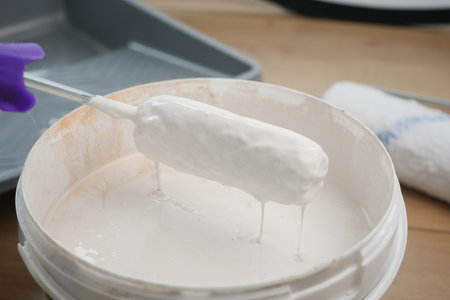 Painting with a roller dipped in white paint on a trayの写真素材
