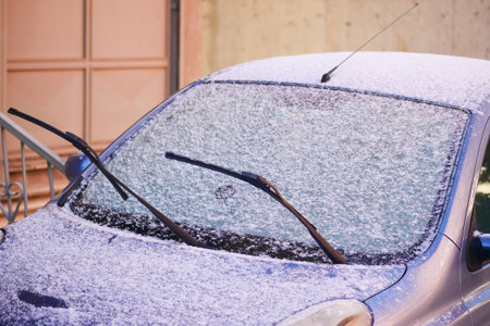 Snow covers car windshield in a quiet urban street during winterの写真素材
