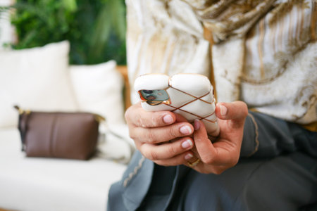 Person using smartphone while sitting on a sofa in a cozy spaceの写真素材