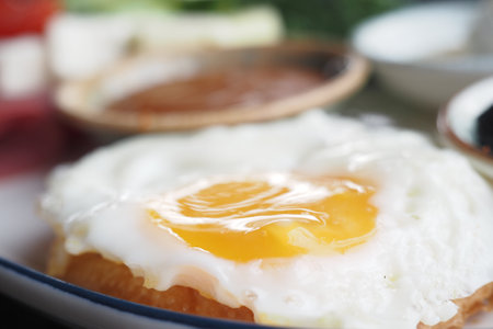 Fried egg with a runny yolk displayed on a vibrant breakfast plateの写真素材