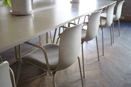 Stylish chairs arranged neatly around a spacious dining table indoorsの写真素材
