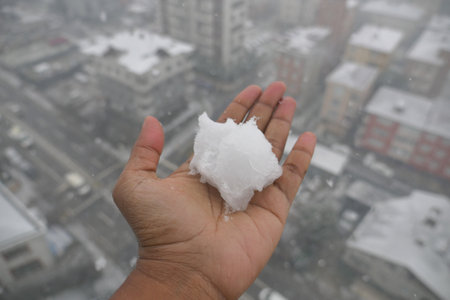 Snowball in palm during urban snowstorm on a winter dayの写真素材