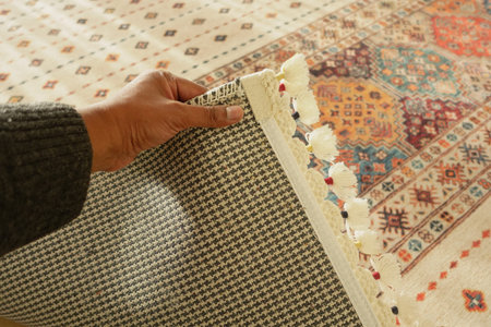 Hand gripping a colorful woven rug in a cozy room