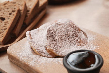 Tasty pancakes with syrup and powdered sugar on wood