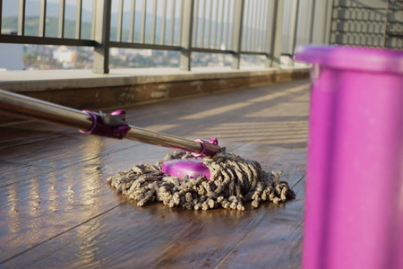 Cleaning a balcony floor with a mop during daytimeの写真素材