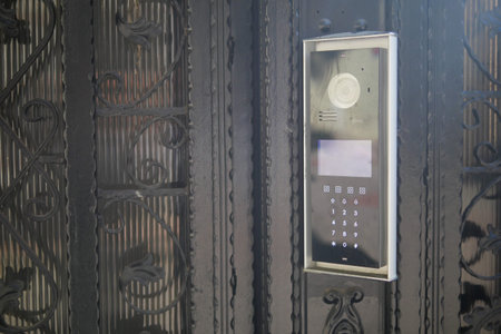 Modern intercom system mounted on an ornate black gate