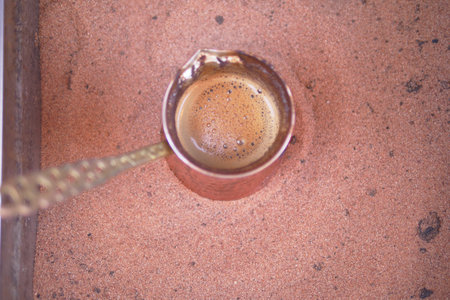 turkish coffee in copper pot on warm sand in outdoor settingの写真素材