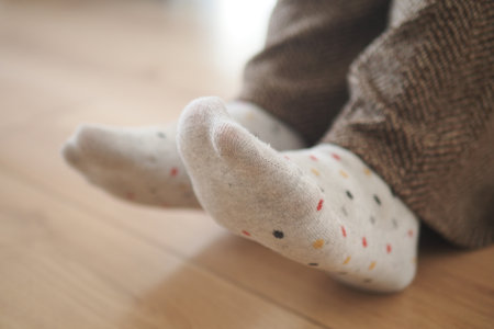 Cozy feet in colorful socks relaxing on a wooden floorの写真素材