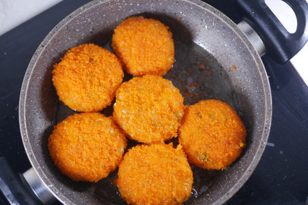 Delicious orange fritters being fried in a pan on a stoveの写真素材