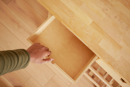 Hand pulling out a drawer in a wooden cabinet at homeの写真素材
