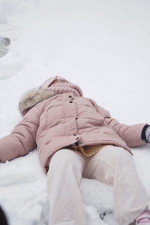 Child plays joyfully in fresh snow on a winter day outdoors