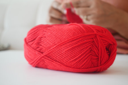 Bright red yarn ball on a table during a cozy crafting sessionの写真素材