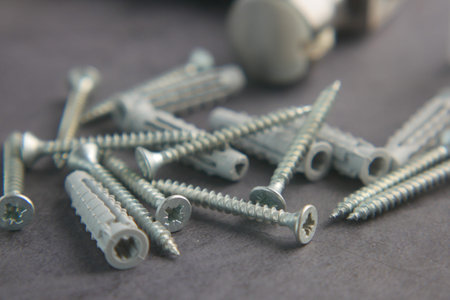 Collection of small metal screws scattered on a gray surface
