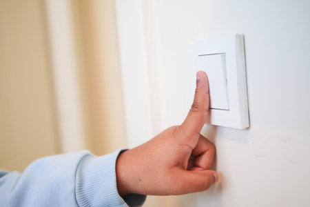 Child turning off light switch in living room during daylight hours