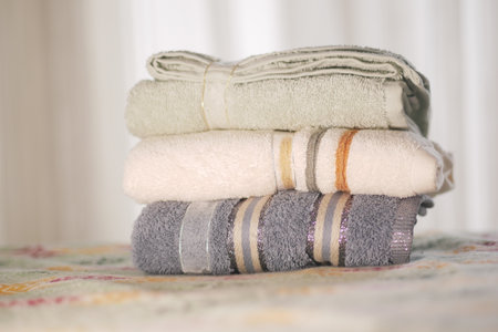 Soft towels stacked neatly on a bedの写真素材