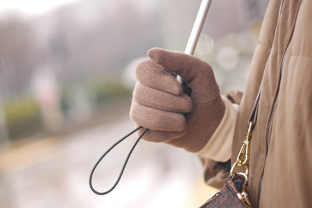 Person holding an umbrella while wearing brown gloves outdoorsの写真素材