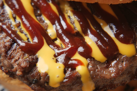 Juicy hamburger topped with mustard and barbecue sauce on a bunの写真素材