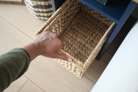 Hand reaching for a woven basket in a modern homeの写真素材