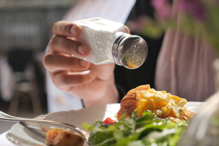Adding seasoning to a fresh salad with croissantの写真素材
