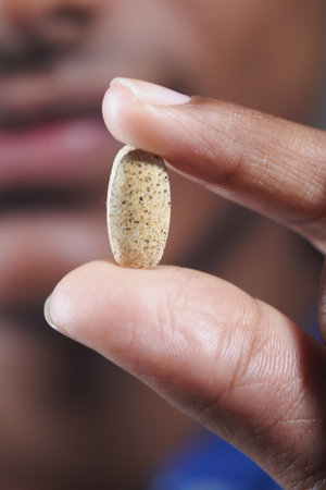 Close-up of a hand holding a supplement tabletの写真素材