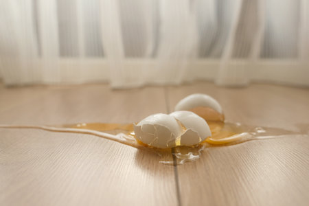 Eggs break on wooden floor creating a messy spillの写真素材