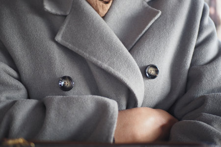 Warm grey coat wrapped around arms in cozy indoor settingの写真素材