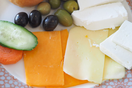 Delicious assortment of cheese and vegetables on a plateの写真素材