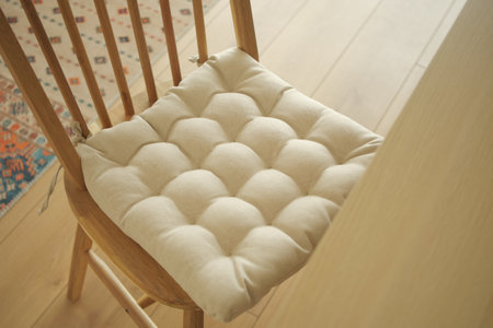 Cozy cushion sits on a wooden chair in a bright roomの写真素材