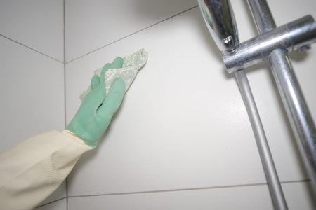 Cleaning bathroom tiles in a shower area with glovesの写真素材