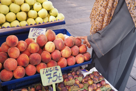 Woman shopping for fresh peaches at a local marketの写真素材