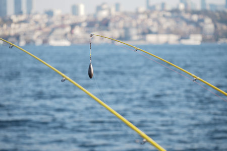 Fishing rods lined up by the water in a coastal cityの写真素材