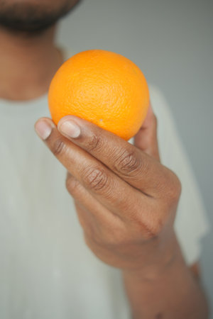 Holding an orange in a hand during a casual momentの写真素材
