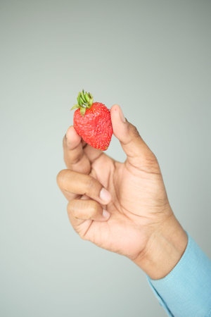 Holding a heart-shaped strawberry in handの写真素材