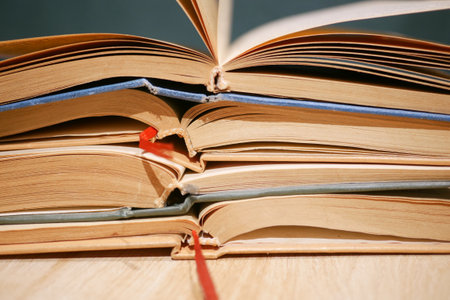 Stacked open books with colorful bookmarks on a wooden tableの写真素材