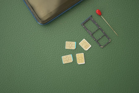 Multiple SIM cards and a tray placed on a green surfaceの写真素材