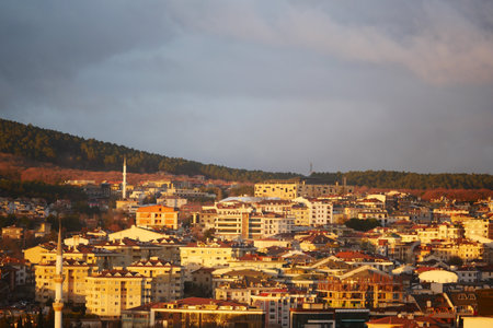 Sunset over a bustling cityscape in a hilly regionの写真素材