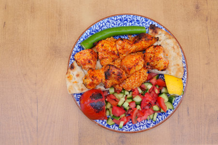 Grilled chicken with fresh vegetables and bread on a platterの写真素材