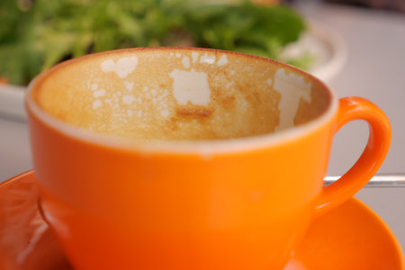 Empty orange coffee cup with remnants at cafe tableの写真素材