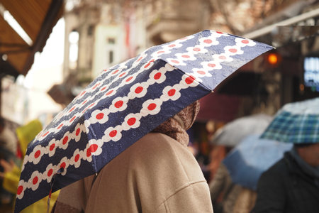 Person under colorful umbrella in rainy city streetの写真素材