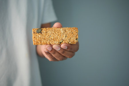 Healthy snack bar held in hand against a simple backgroundの写真素材