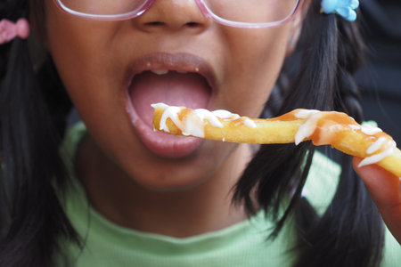 Child enjoys tasty fries with sauce during outdoor meal