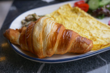Croissant and omelette served with fresh salad
