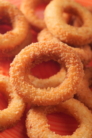 Delicious crispy onion rings piled on a vibrant plateの写真素材