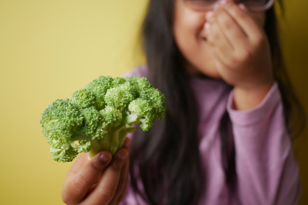 Child holds broccoli while laughing in the kitchenの写真素材